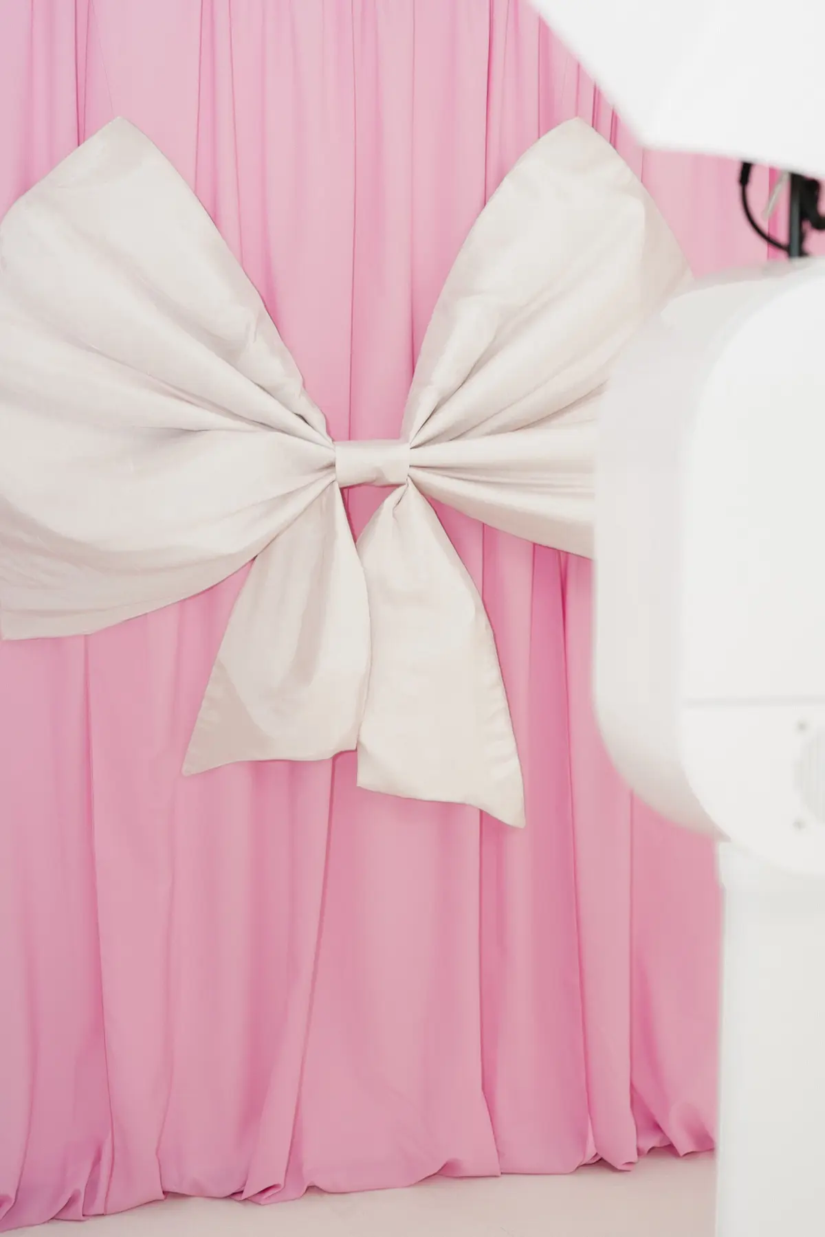 Bridal photo booth with coordinated pink bow backdrop and props